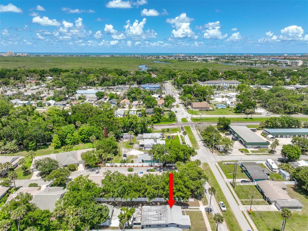 An aerial view shows a single-story house with a gray roof surrounded by trees — 607 WAYNE AVENUE, NEW SMYRNA BEACH, FL