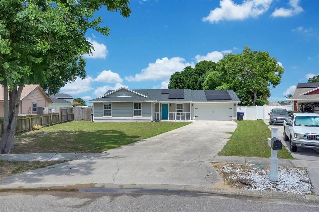 A single-story house with light gray siding, a blue front door, and rooftop solar panels — 8115 WINDY HILL WAY, ORLANDO, FL
