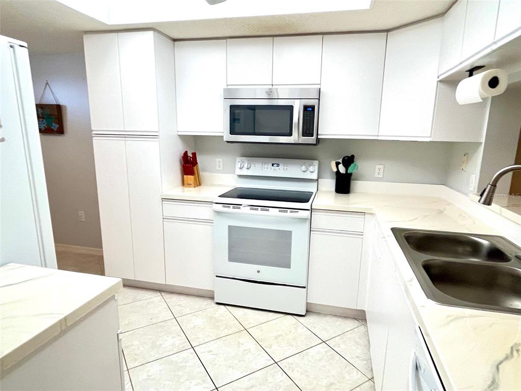 A kitchen with white cabinets, white appliances, and light-colored countertops — 6507 STONE RIVER ROAD UNIT 210, BRADENTON, FL