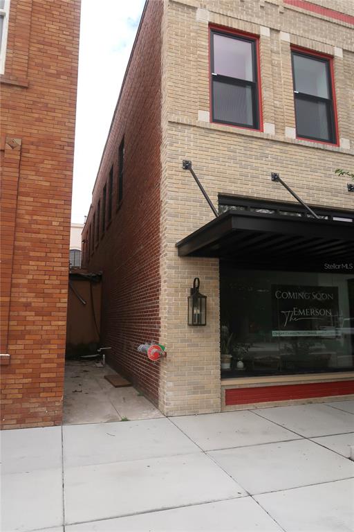 A brick building exterior features a storefront window with a sign and a narrow alleyway — 244 E PARK AVENUE, LAKE WALES, FL