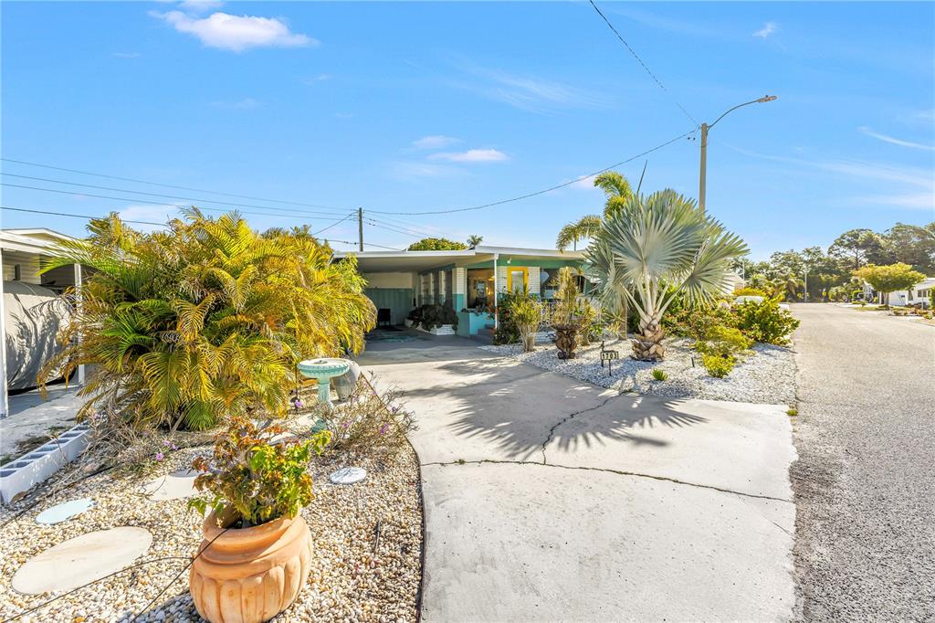 A single-story house with a carport, palm trees, and a gravel yard under a blue sky — 1703 MINNESOTA AVENUE, BRADENTON, FL