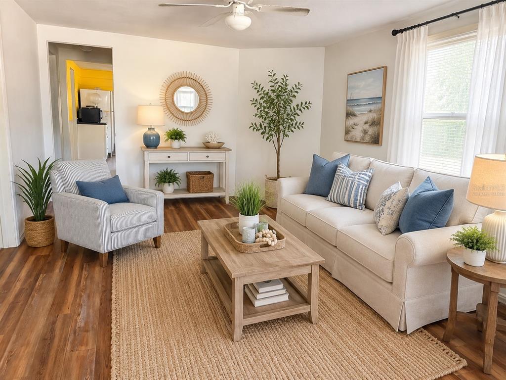 A living room with wood-look flooring, a coffee table, two chairs, and red patterned curtains — 2178 7TH STREET, SARASOTA, FL