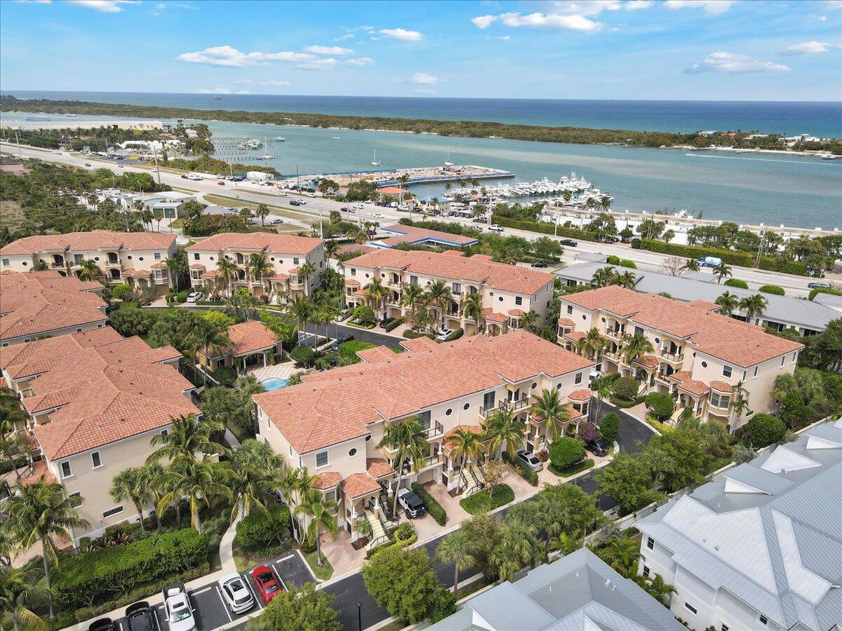 An aerial view shows a multi-story residential complex with terracotta roofs near a coastal marina — 502 Del Sol Circle, Tequesta FL 33469, TEQUESTA, FL