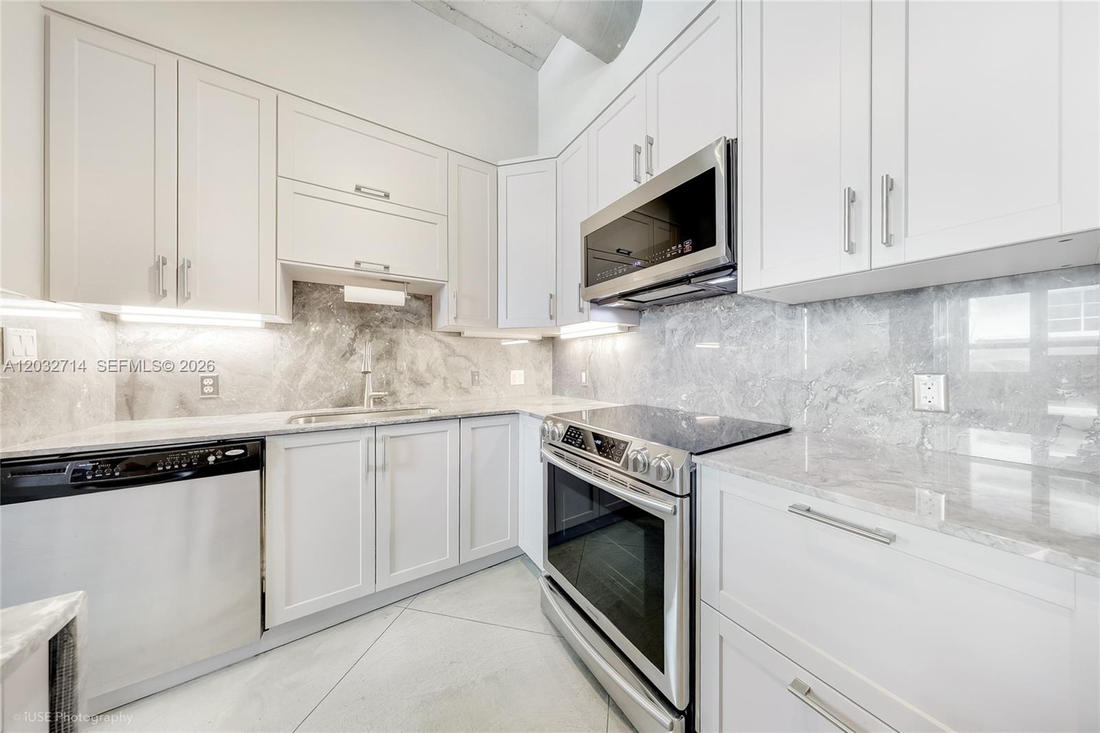 A modern kitchen features white cabinets, stainless steel appliances, and gray marble countertops and backsplash — 2001 Biscayne Blvd # 2311, Miami FL 33137, MIAMI, FL