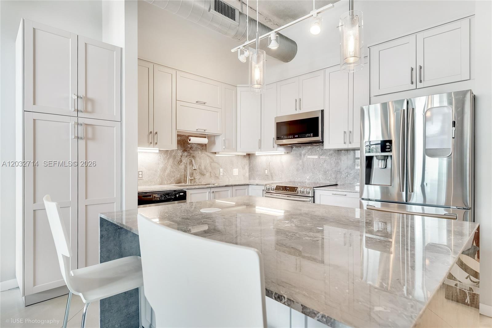 A modern kitchen features white cabinetry, marble countertops, stainless steel appliances, and a large island — 2001 Biscayne Blvd # 2311, Miami FL 33137, MIAMI, FL