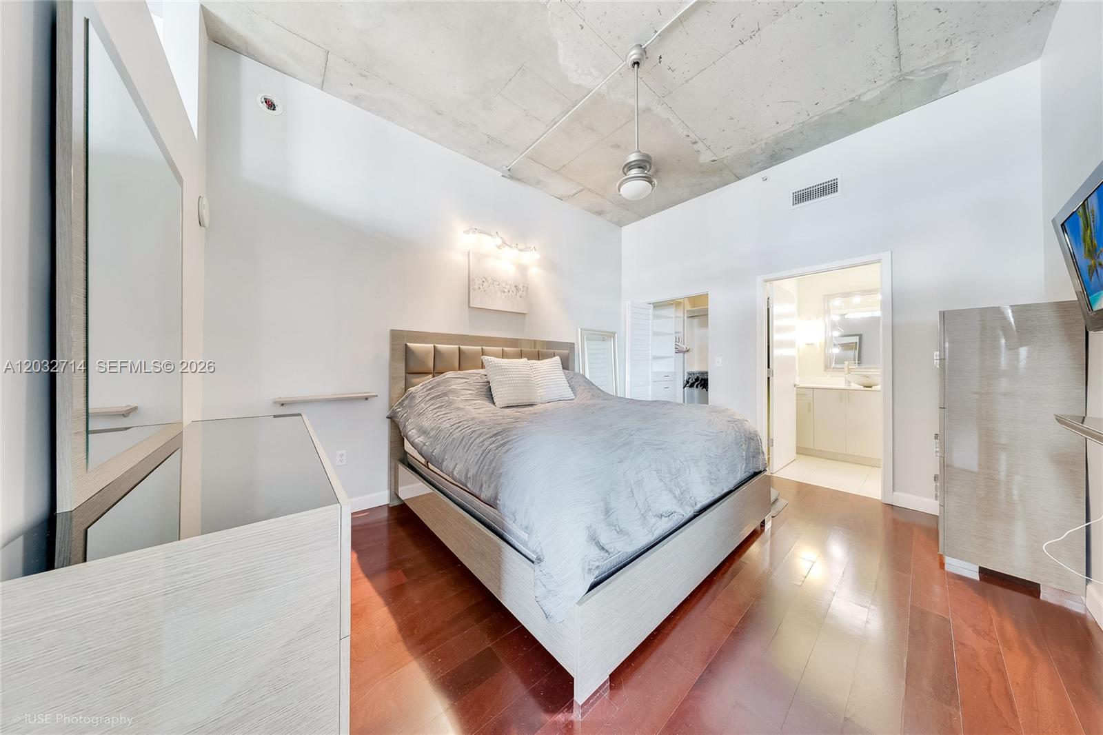 A bedroom features a bed, hardwood floors, and an exposed concrete ceiling — 2001 Biscayne Blvd # 2311, Miami FL 33137, MIAMI, FL