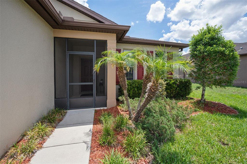 A concrete walkway leads to the screened front entryway of a suburban home — 2118 TRILLIUM BOULEVARD, BROOKSVILLE, FL