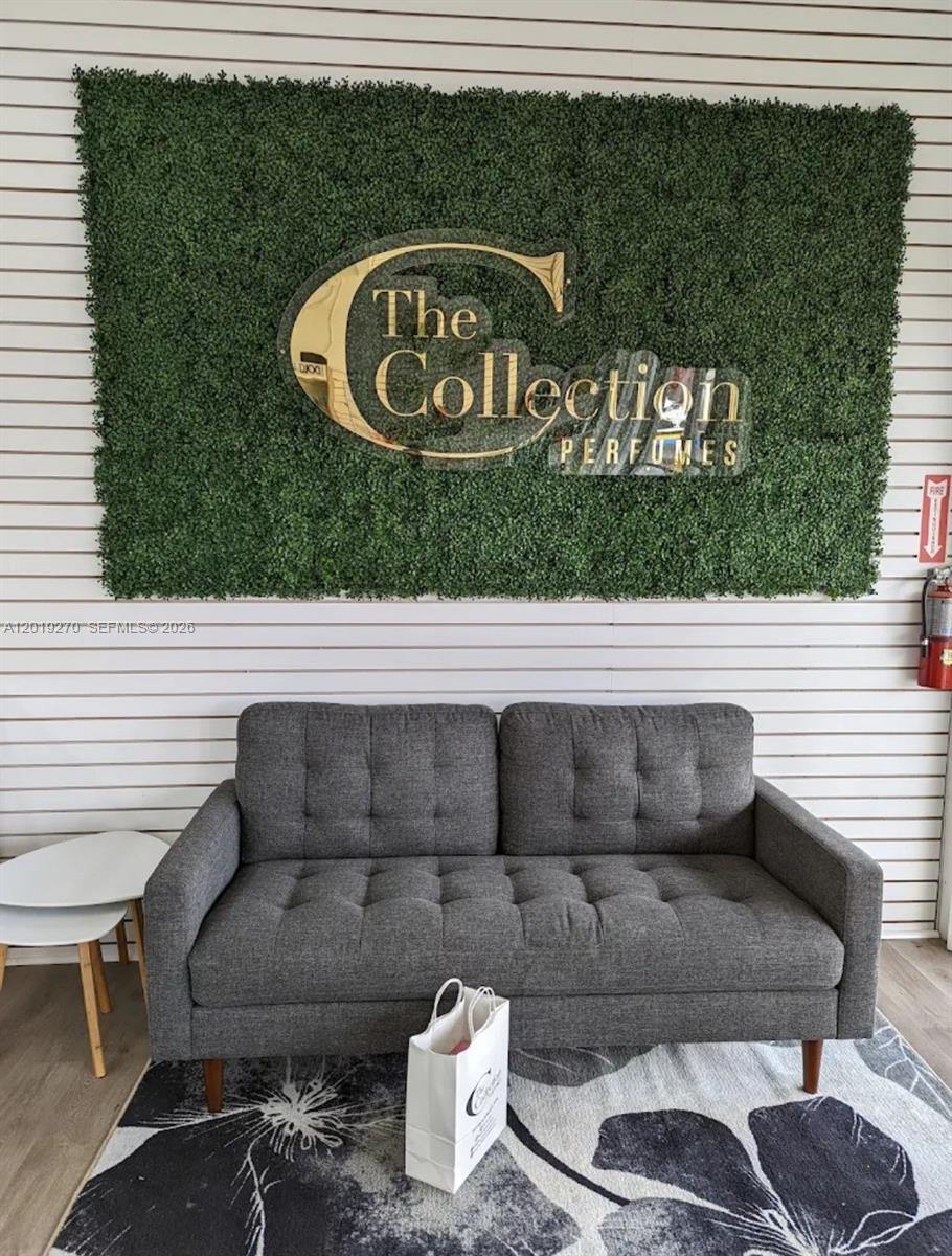 A grey tufted sofa sits in front of a green wall with a store logo — 1917 NW 20th St, Miami FL 33142, MIAMI, FL