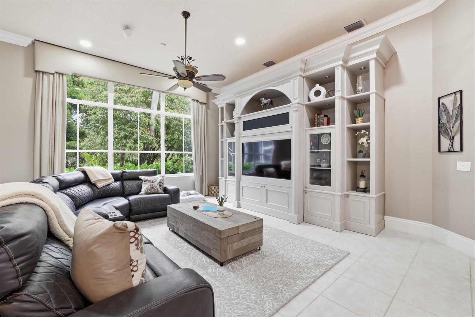 A living room features a large sectional sofa, a wooden coffee table, and built-in shelving — 856 Forest Glen Lane, Wellington FL 33414, WELLINGTON, FL