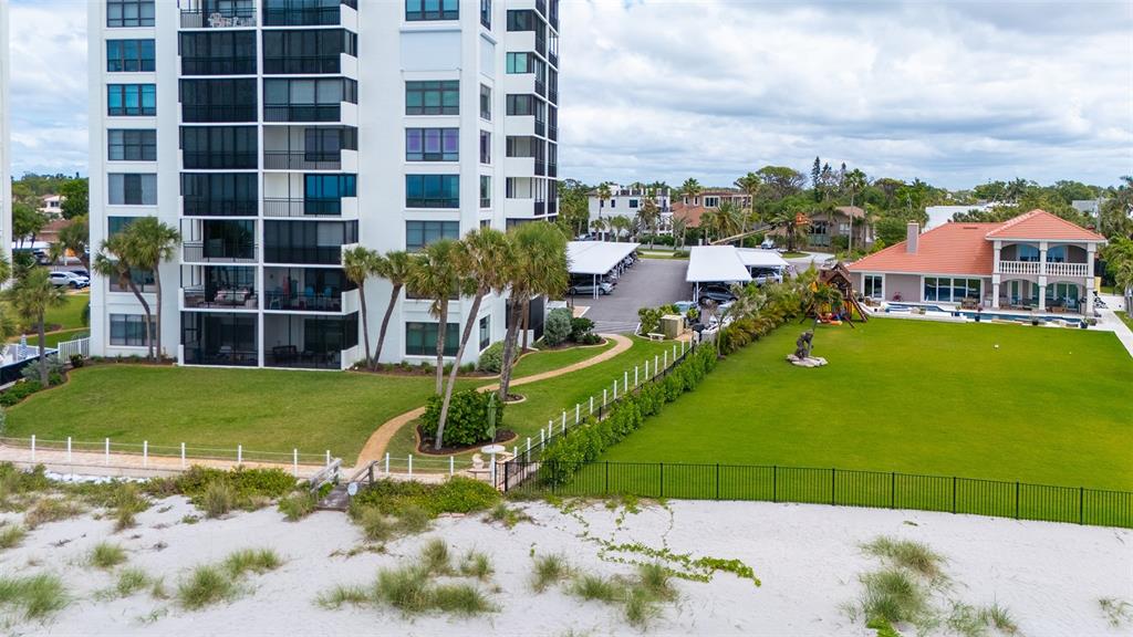 An aerial view shows a tall apartment building next to a house with a lawn — 621 ALHAMBRA ROAD, VENICE, FL
