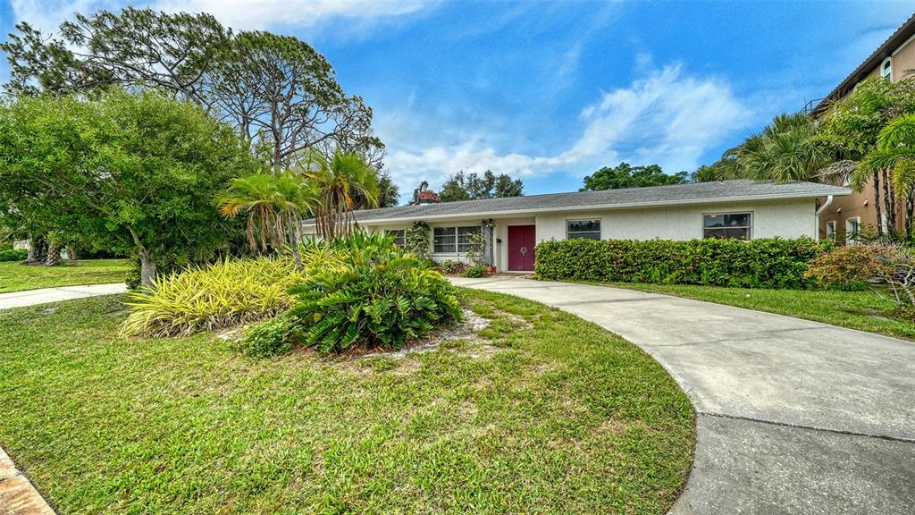 A single-story house with a white exterior, a red front door, and a concrete driveway — 621 ALHAMBRA ROAD, VENICE, FL