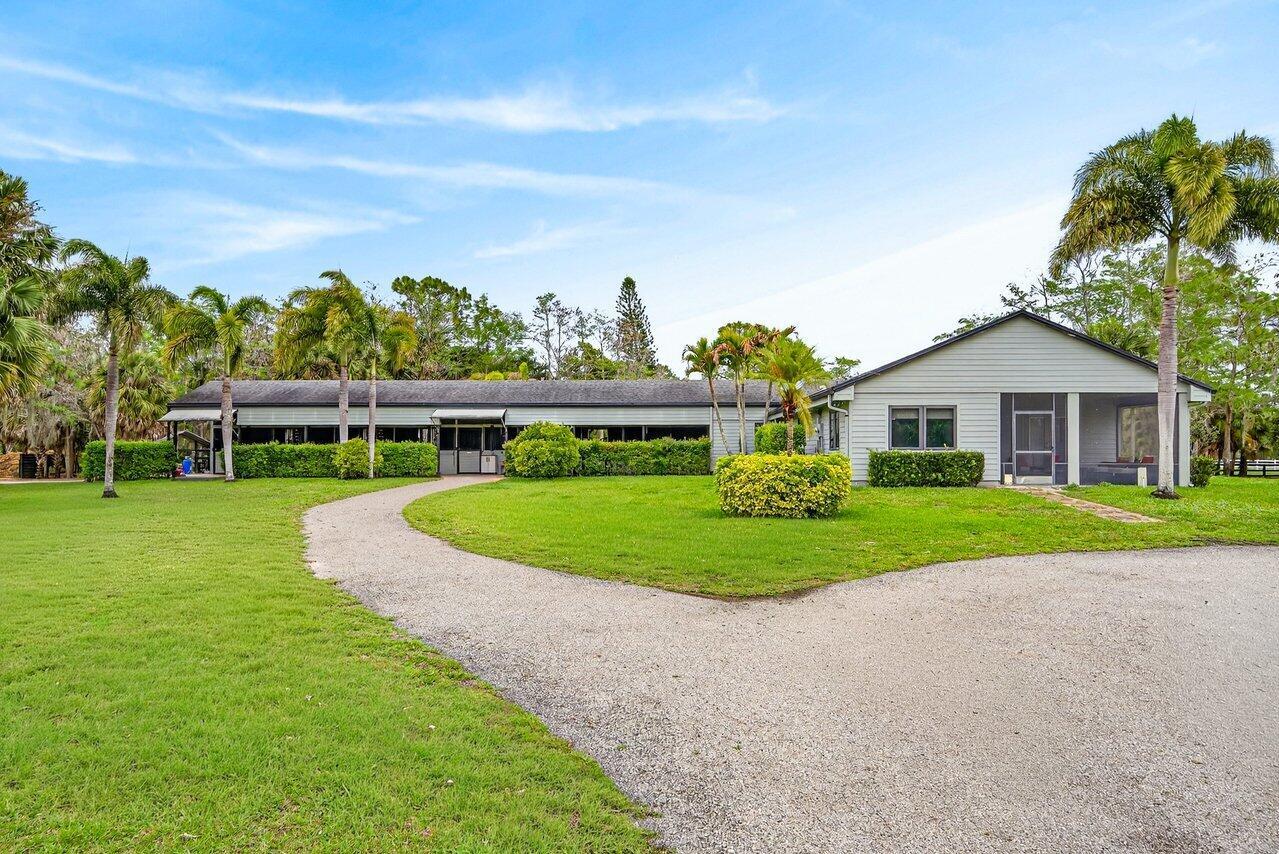 A single-story house with light siding and a screened porch sits on a grassy lot — 2741 Buck Ridge Trail, Loxahatchee FL 33470, LOXAHATCHEE, FL