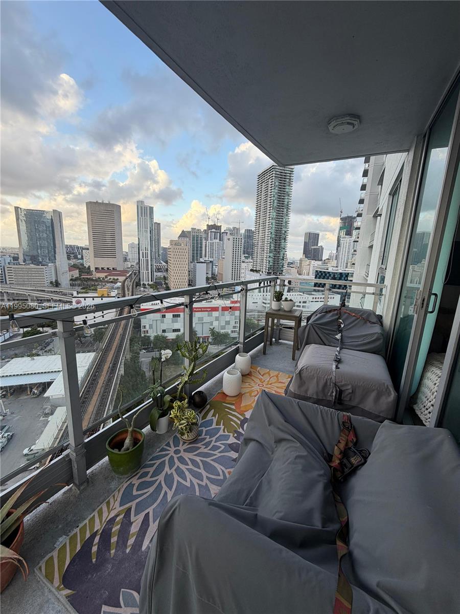 A balcony with outdoor furniture and potted plants overlooks a city skyline and train tracks — 90 SW 3RD STREET # 2112, Miami FL 33130, MIAMI, FL