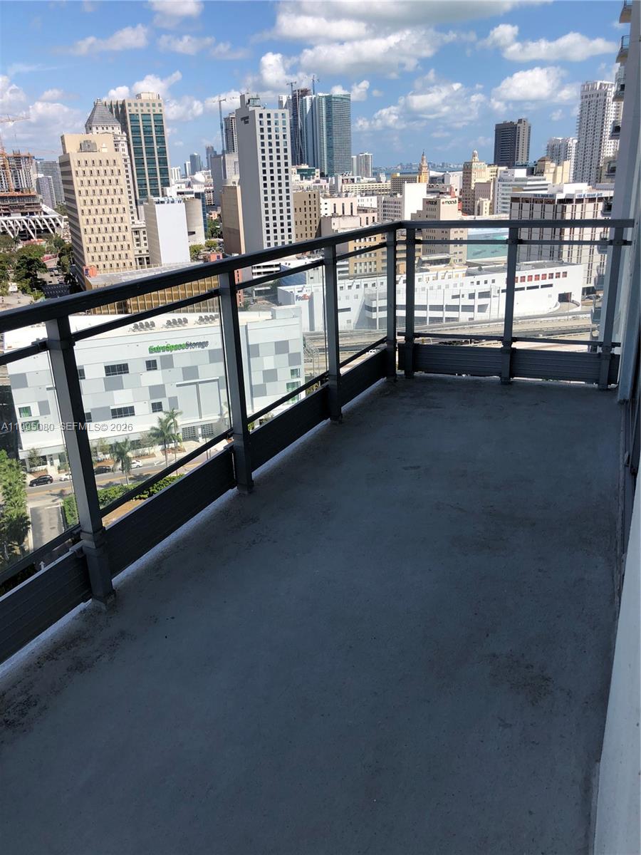 A balcony with a glass railing overlooks a city skyline with various high-rise buildings — 90 SW 3RD STREET # 2112, Miami FL 33130, MIAMI, FL
