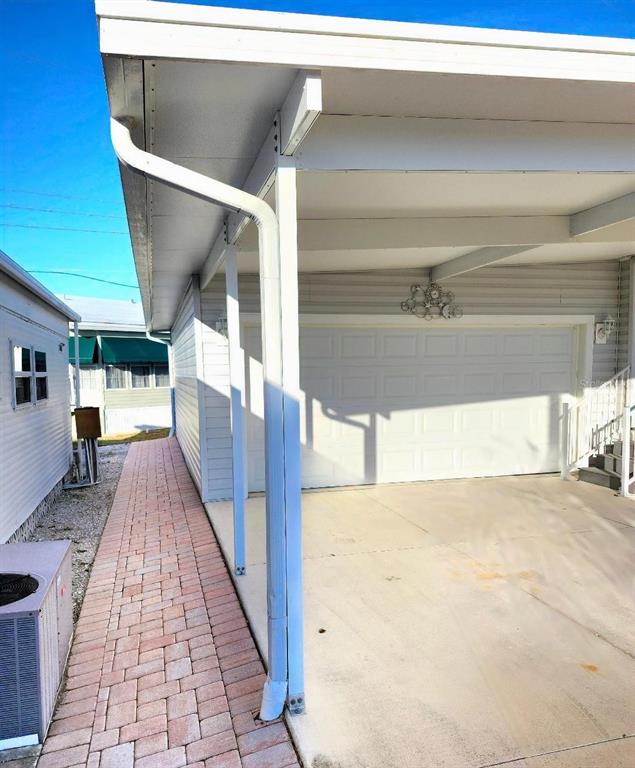 A white carport with a brick walkway sits beside a house with a garage door — 1709 MINNESOTA AVENUE, BRADENTON, FL