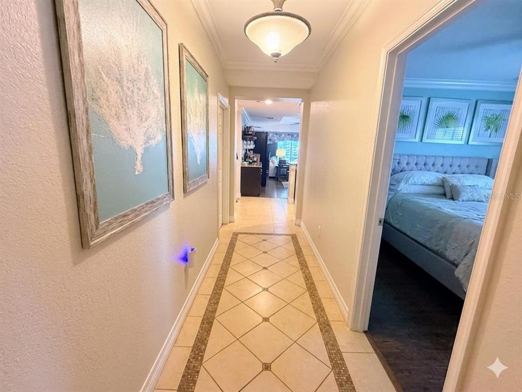 A hallway with tile flooring leads to a bedroom on the right and another room — 1100 SUNSET VIEW CIRCLE S UNIT 304, KISSIMMEE, FL