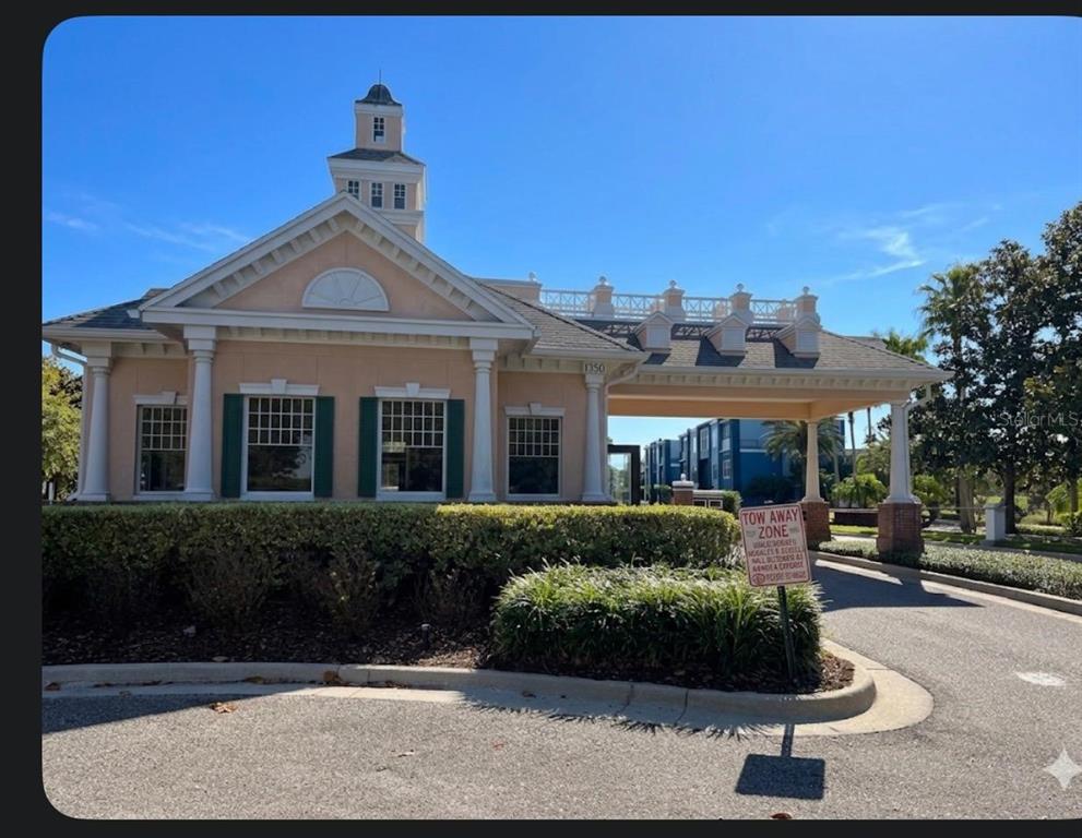 A peach-colored community clubhouse with a cupola and a covered drive-through entrance — 1100 SUNSET VIEW CIRCLE S UNIT 304, KISSIMMEE, FL