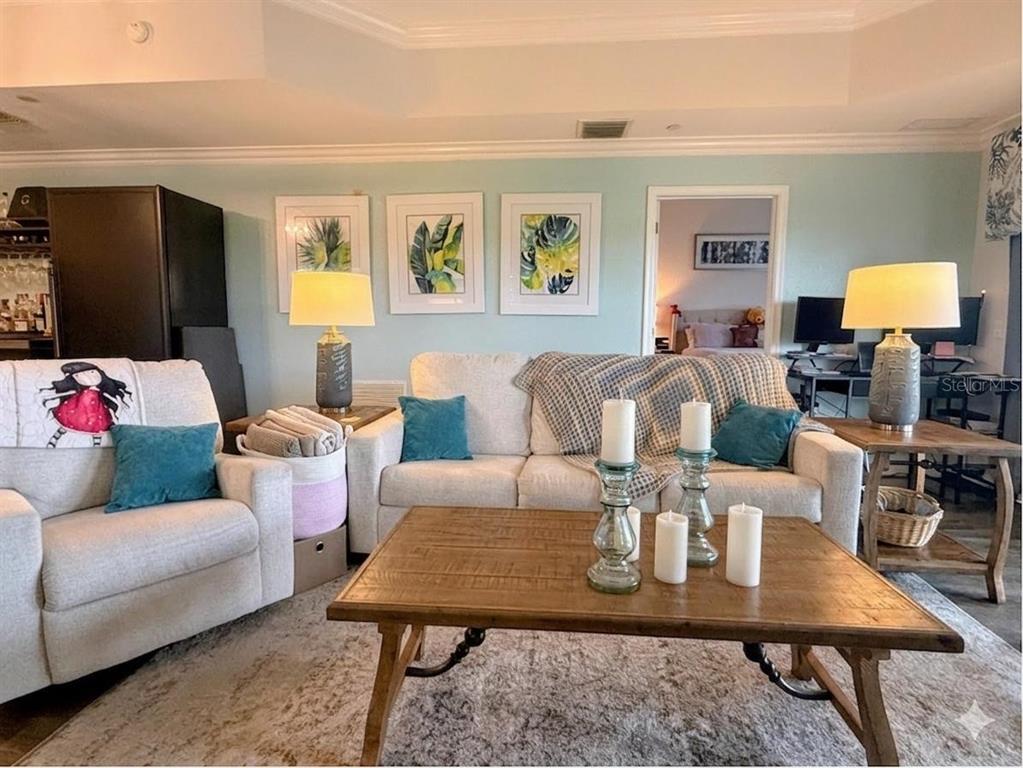 A living room features a beige sofa, matching armchair, wooden coffee table, and wall art — 1100 SUNSET VIEW CIRCLE S UNIT 304, KISSIMMEE, FL