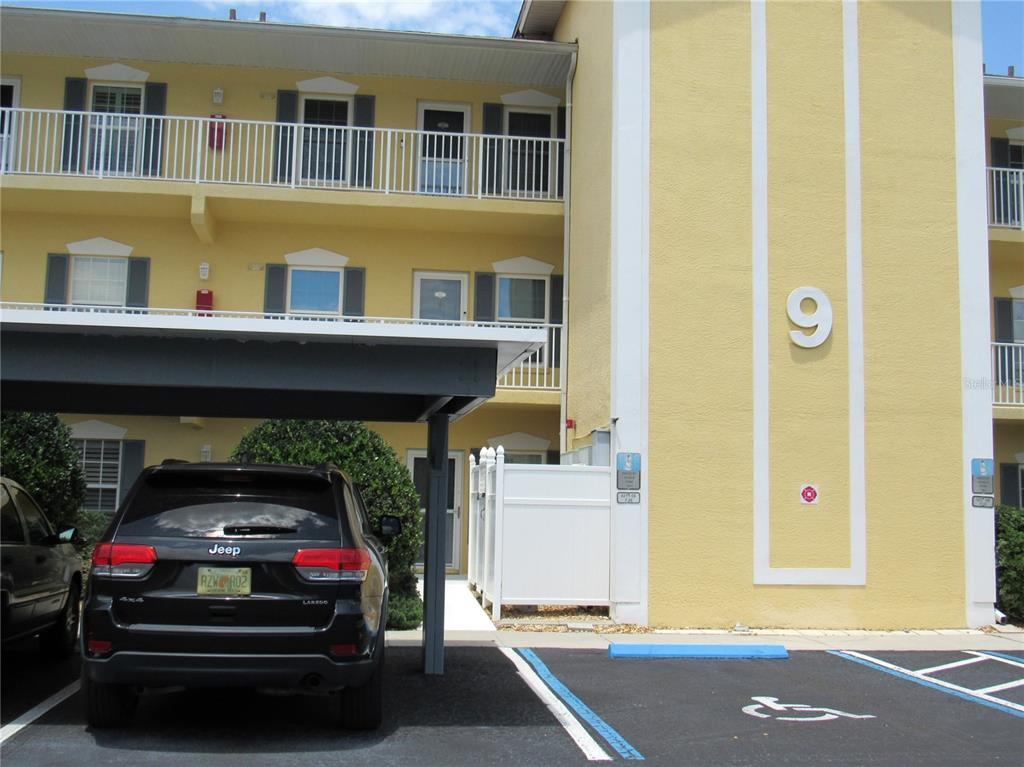 A three-story yellow apartment building with a covered parking space and a handicap parking spot — 175 KINGS HIGHWAY UNIT 933, PUNTA GORDA, FL