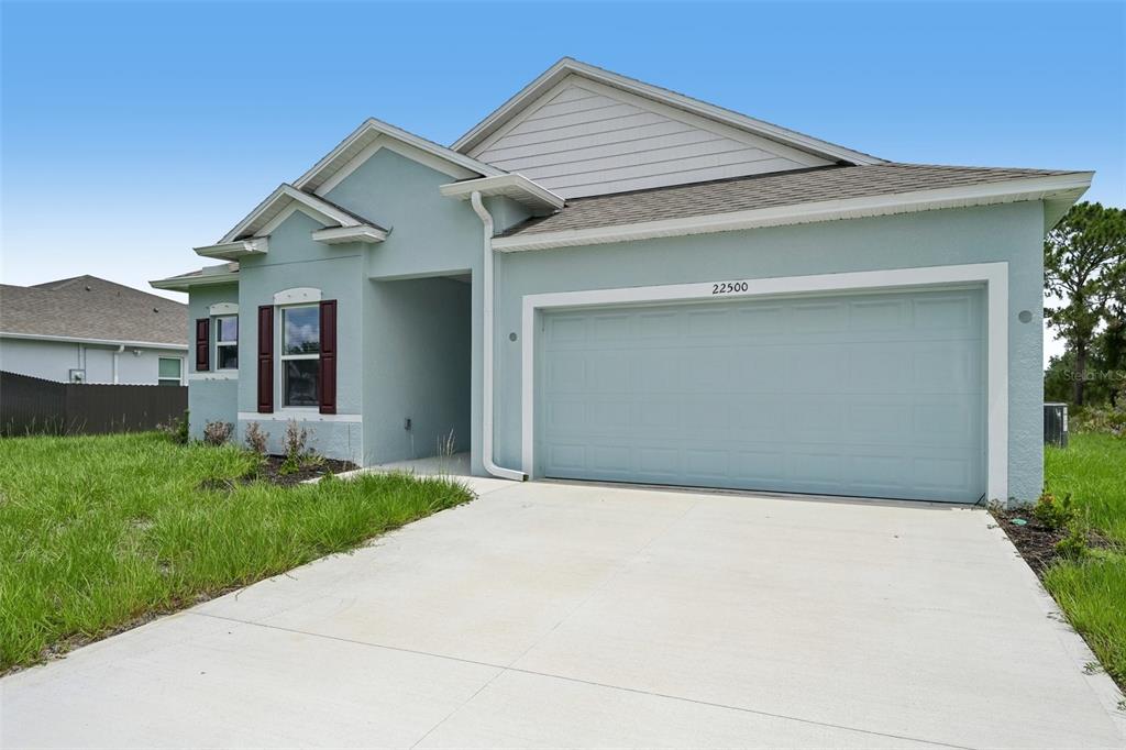 A light blue single-story house features a two-car garage and a concrete driveway — 22500 PROVANCE AVENUE, PORT CHARLOTTE, FL