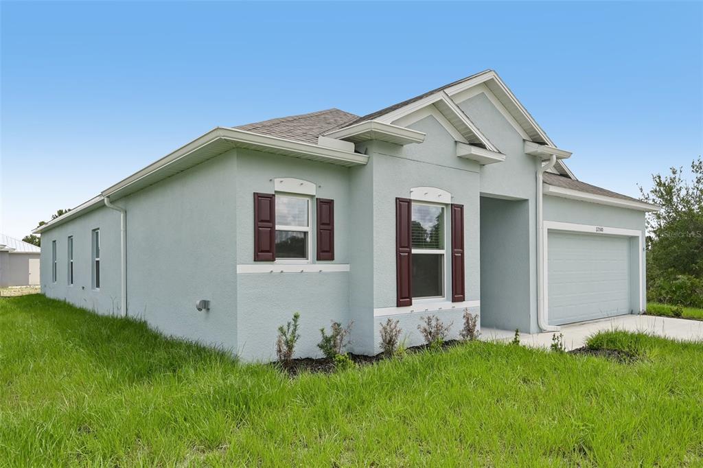 A light blue single-story house with a two-car garage and dark red window shutters — 22500 PROVANCE AVENUE, PORT CHARLOTTE, FL