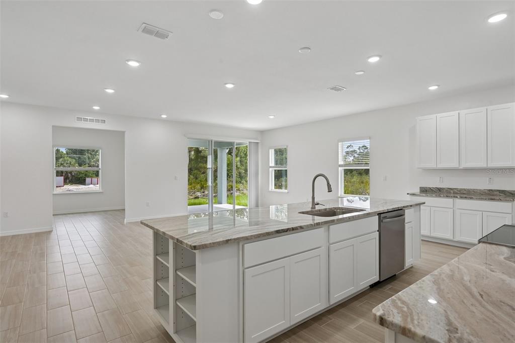 A modern kitchen features white cabinets, a large granite-topped island, and light tile flooring — 22500 PROVANCE AVENUE, PORT CHARLOTTE, FL