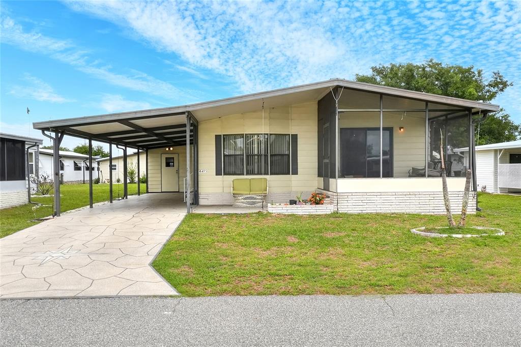 A single-story manufactured home with a carport, a screened-in porch, and a patterned concrete driveway — 6473 PEPPERTREE PATH NE, WINTER HAVEN, FL