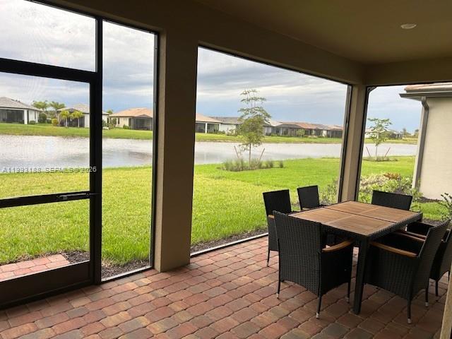 A screened-in patio features a dining set overlooking a lake and residential neighborhood — 6385 Honor Way, Ave Maria FL 34142, AVE MARIA, FL