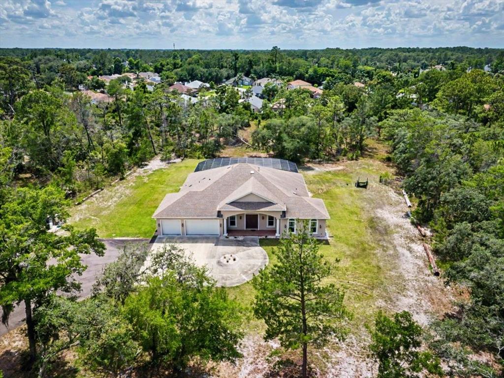 An aerial view of a single-story house with a screened pool enclosure and circular driveway — 1812 TAYLOR ROAD, PORT ORANGE, FL