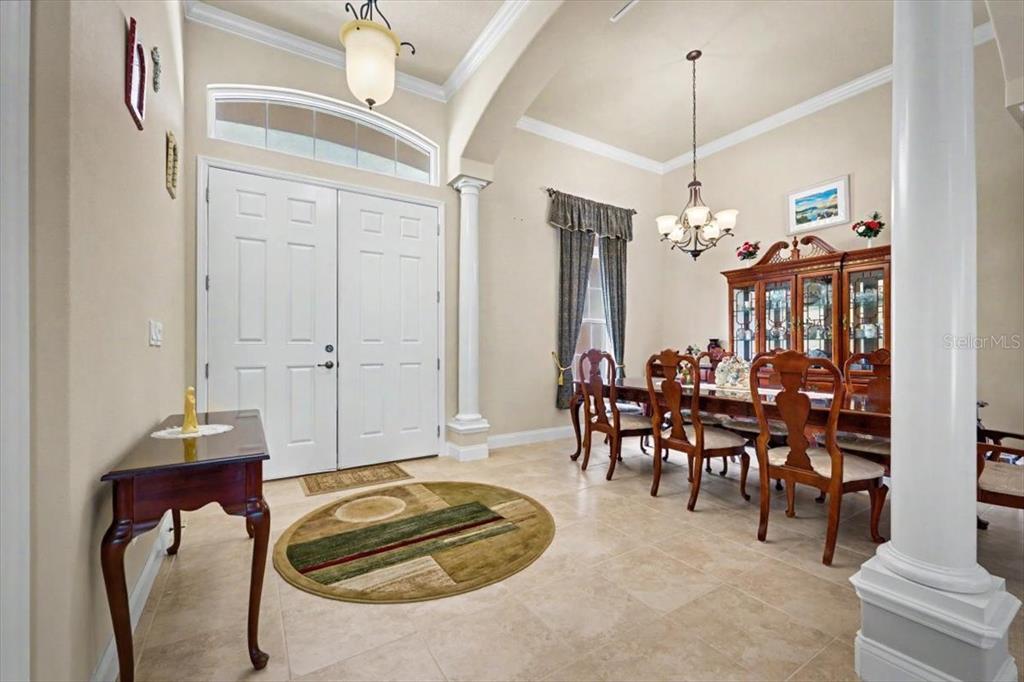 A dining room with tile floors, a chandelier, and a double-door entryway — 1812 TAYLOR ROAD, PORT ORANGE, FL