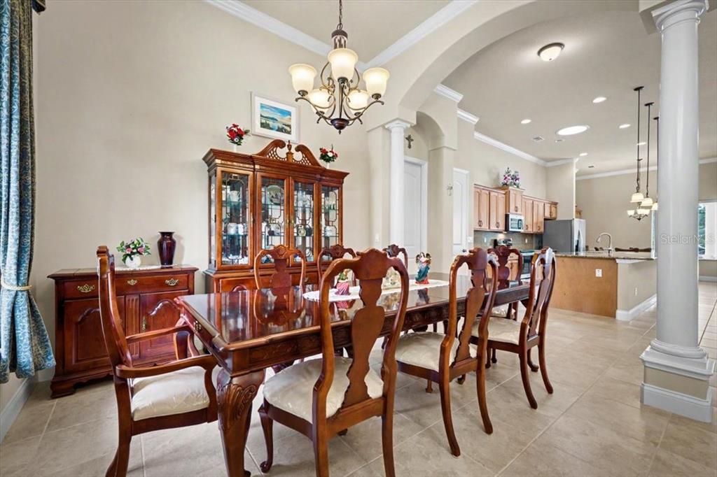 A formal dining room features a wooden table and chairs, a hutch, and tile flooring — 1812 TAYLOR ROAD, PORT ORANGE, FL