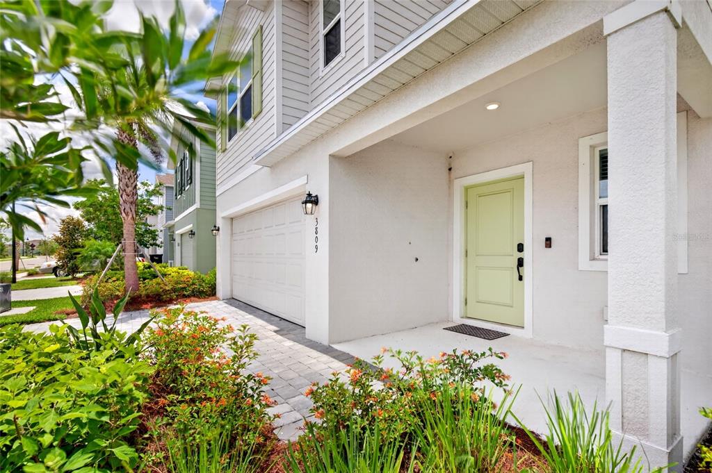 A light-colored house exterior features a pale green front door and a paved driveway — 3809 AMBERSWEET CROSSING, PARRISH, FL