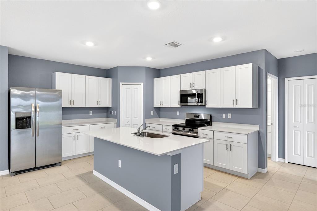 A kitchen features white cabinets, stainless steel appliances, a center island, and gray walls — 3809 AMBERSWEET CROSSING, PARRISH, FL