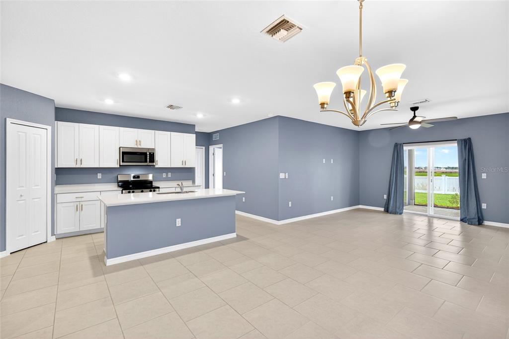 A kitchen with white cabinets and a breakfast bar opens into a spacious living area — 3809 AMBERSWEET CROSSING, PARRISH, FL