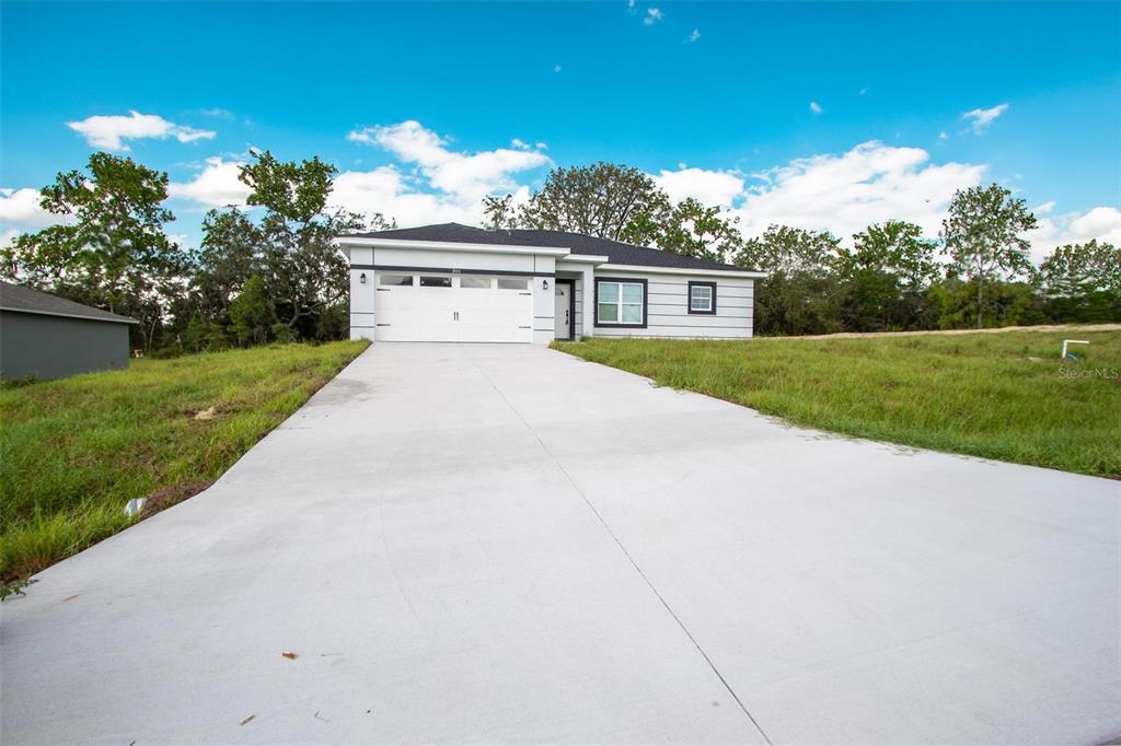 A single-story house with a white garage and concrete driveway sits on a grassy lot — 301 BOWFIN DRIVE, KISSIMMEE, FL