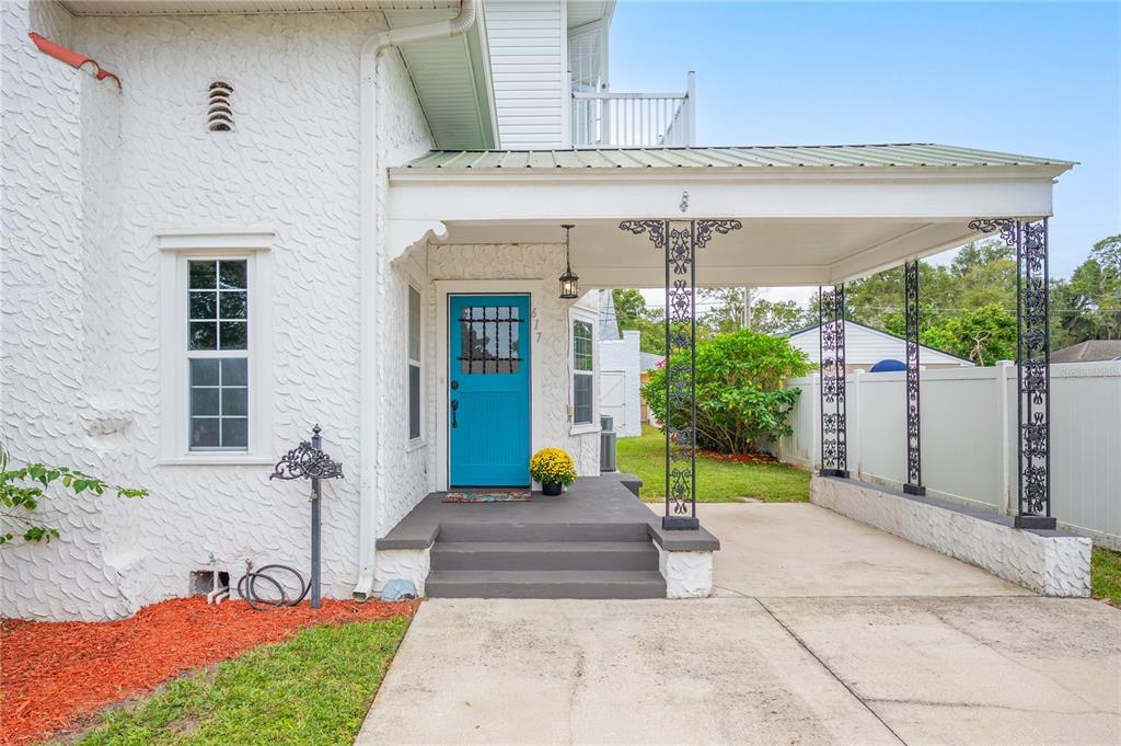 A white stucco house features a bright blue front door and a covered carport area — 617 KERNEYWOOD STREET, LAKELAND, FL
