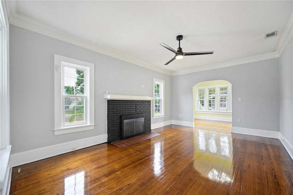 A living room features light gray walls, dark hardwood floors, a black brick fireplace, and ceiling fan — 617 KERNEYWOOD STREET, LAKELAND, FL