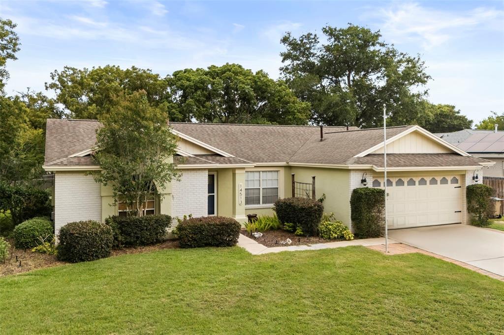 A single-story house with a light-colored brick facade, a two-car garage, and a grassy lawn — 14513 POINTE EAST TRAIL, CLERMONT, FL