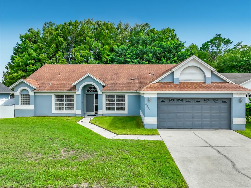 A single-story blue house with a gray garage door and a brown shingled roof — 3020 HARTLAND COURT, ORLANDO, FL