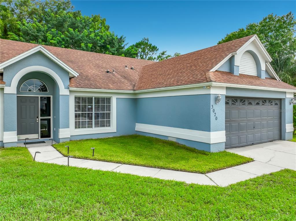 A blue single-story house with a brown shingled roof, white trim, and a two-car garage — 3020 HARTLAND COURT, ORLANDO, FL