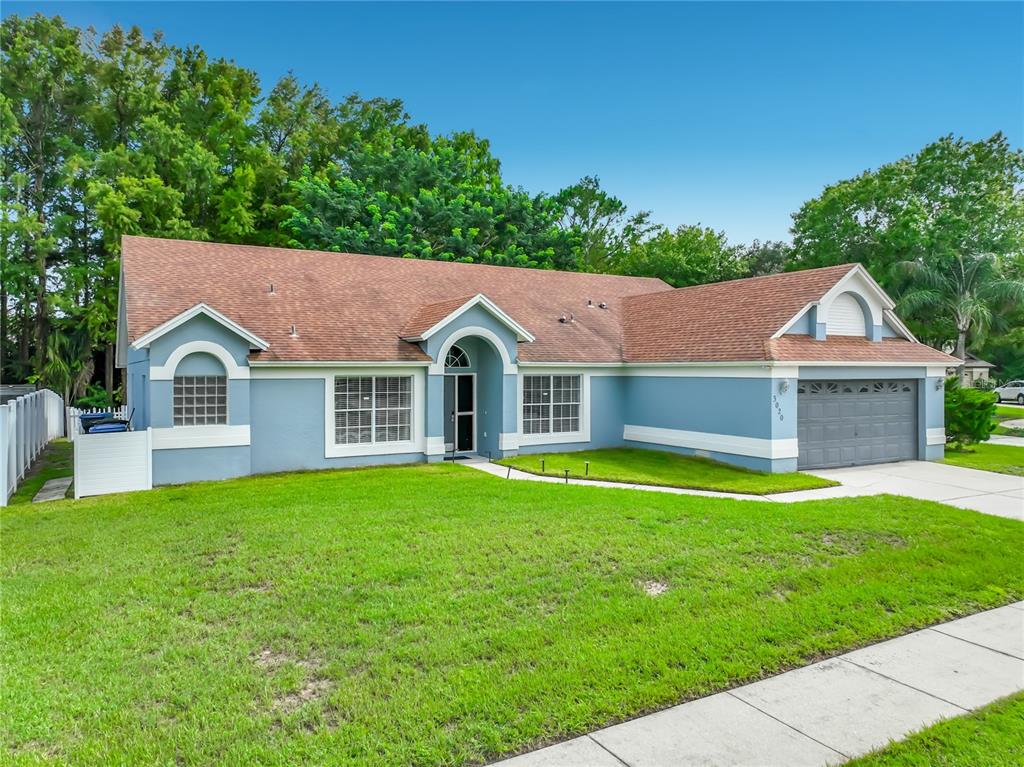 A blue single-story house with a brown shingled roof, arched windows, and a two-car garage — 3020 HARTLAND COURT, ORLANDO, FL