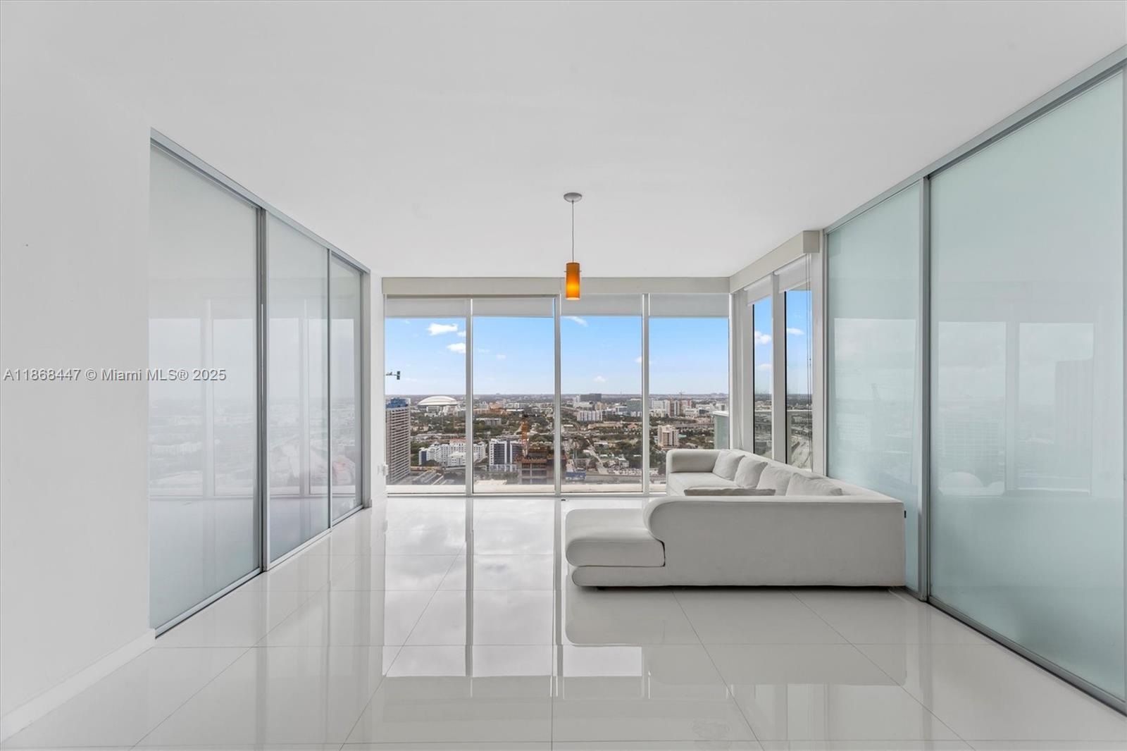 A modern living room features white tile floors, floor-to-ceiling windows, and frosted glass partitions — 1040 Biscayne Blvd # 3106, Miami FL 33132, MIAMI, FL