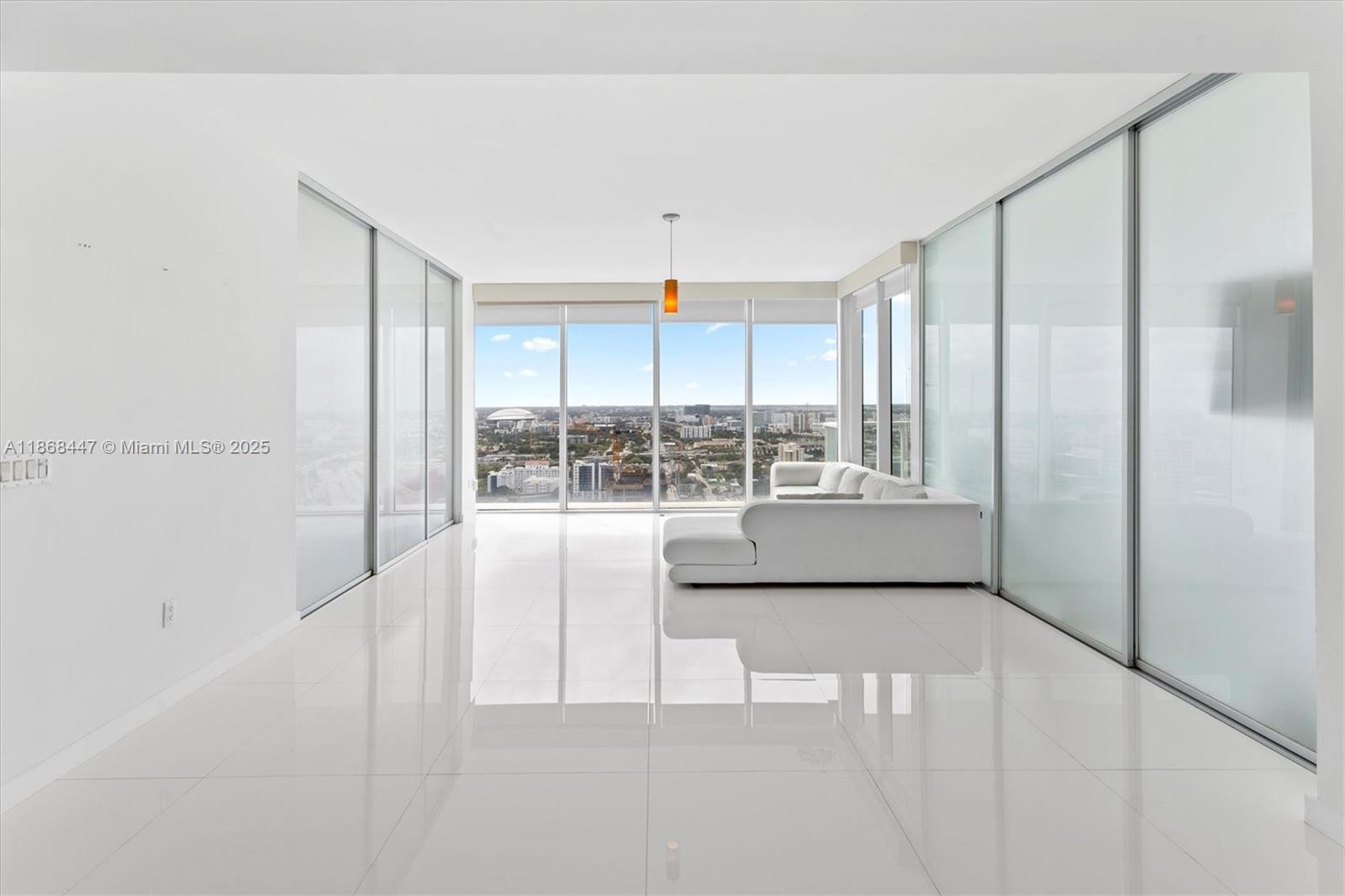 A minimalist living room features white tile floors, floor-to-ceiling windows, and sliding glass walls — 1040 Biscayne Blvd # 3106, Miami FL 33132, MIAMI, FL