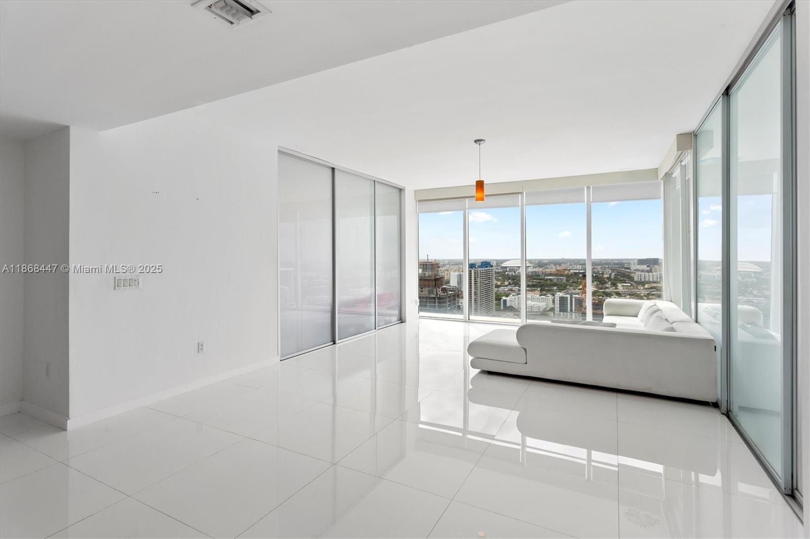 A bright living room features white tile floors, a white sectional sofa, and floor-to-ceiling windows — 1040 Biscayne Blvd # 3106, Miami FL 33132, MIAMI, FL