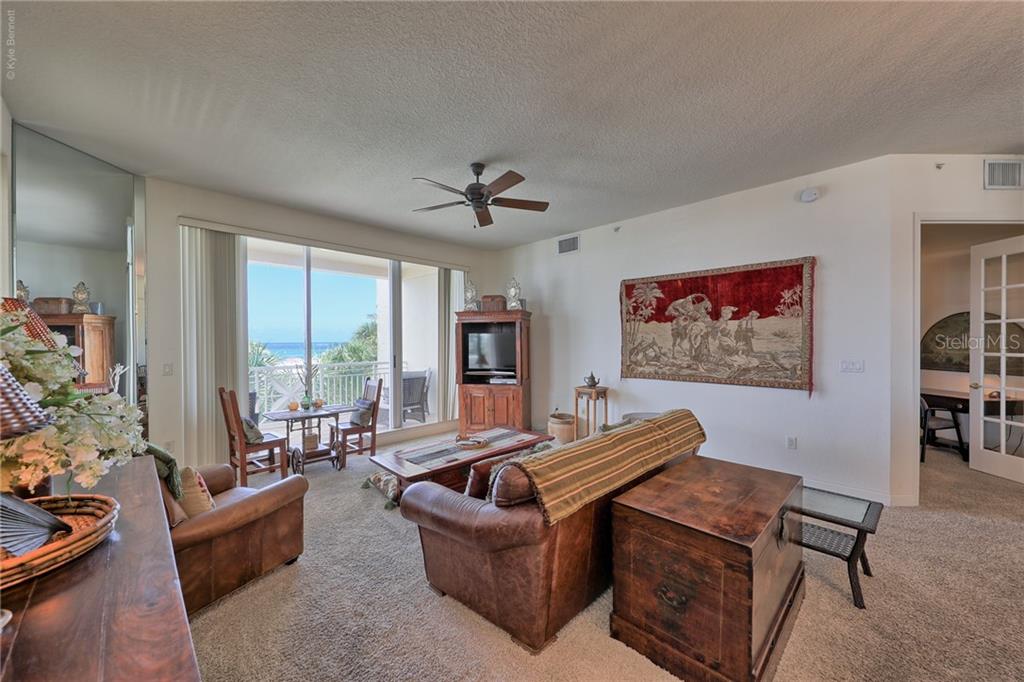 A living room features a leather sofa, a wooden chest, and a balcony overlooking the ocean — 10 PAPAYA STREET UNIT 305, CLEARWATER BEACH, FL