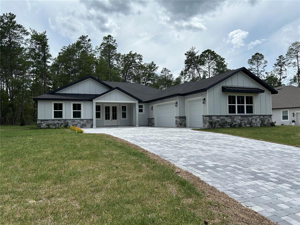 A single-story house with light gray siding, stone accents, and a paved driveway — 3781 N BOXELDER WAY, BEVERLY HILLS, FL