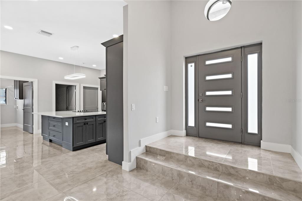 An entryway with a gray front door and tiled steps leads into a modern kitchen area — 541 W LAKE BRANTLEY ROAD, ALTAMONTE SPRINGS, FL