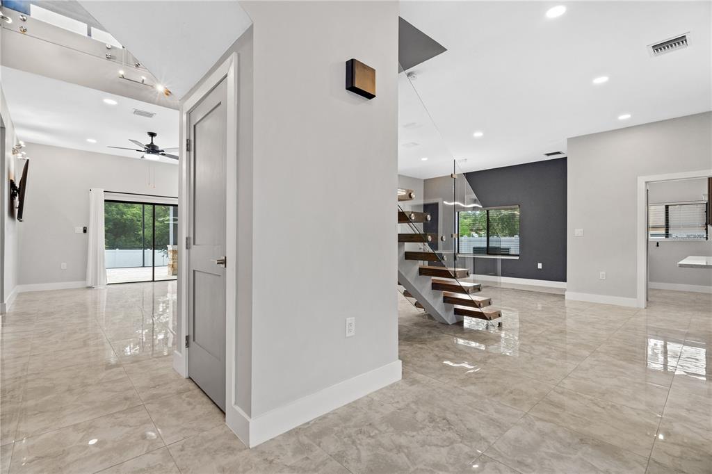 A modern interior features a floating staircase with glass railings and light-colored tile flooring — 541 W LAKE BRANTLEY ROAD, ALTAMONTE SPRINGS, FL