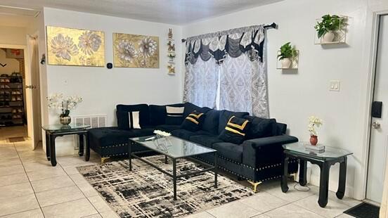A living room features a black sectional sofa, glass-topped tables, and gold-toned wall art — 113 Hilton Drive, Fort Pierce FL 34946, FORT PIERCE, FL