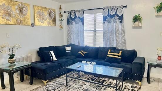 A living room features a dark blue sectional sofa, glass coffee table, and gold wall art — 113 Hilton Drive, Fort Pierce FL 34946, FORT PIERCE, FL